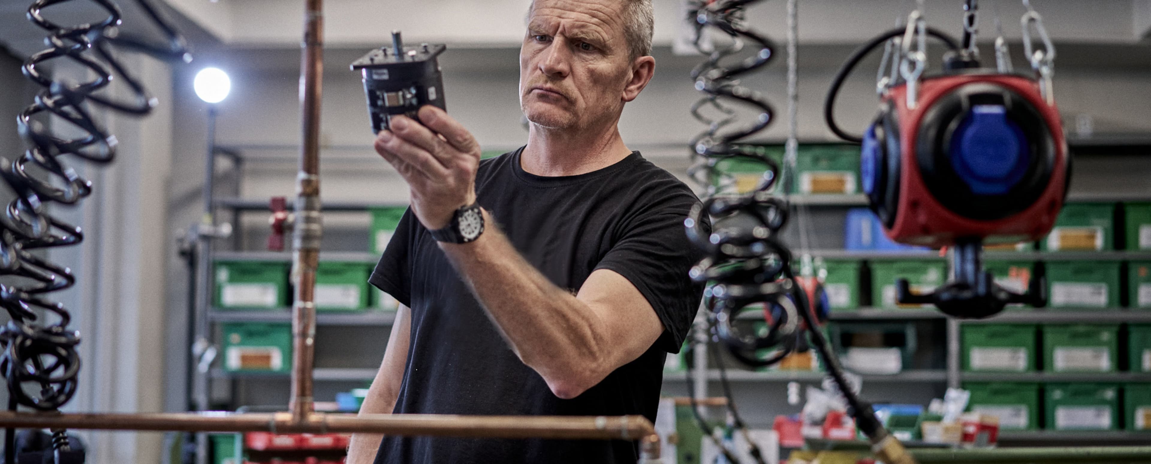 Ein Mitarbeiter von Sälzer, der ein Bauteil für Nockenschalter hochhält. 