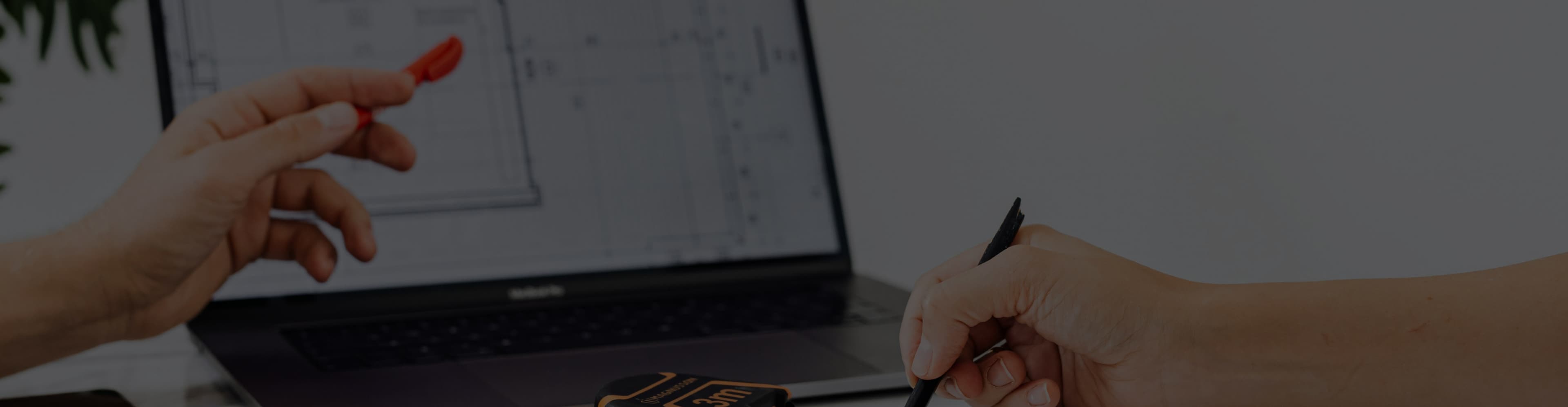 Ein Bildschirm mit Planungssoftware, auf den mehrere Hände zeigen. 